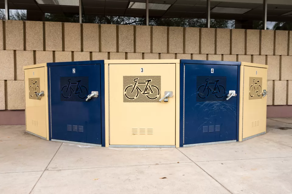 Blue and beige secure bike lockers in underground passageway etched with bicycle logo